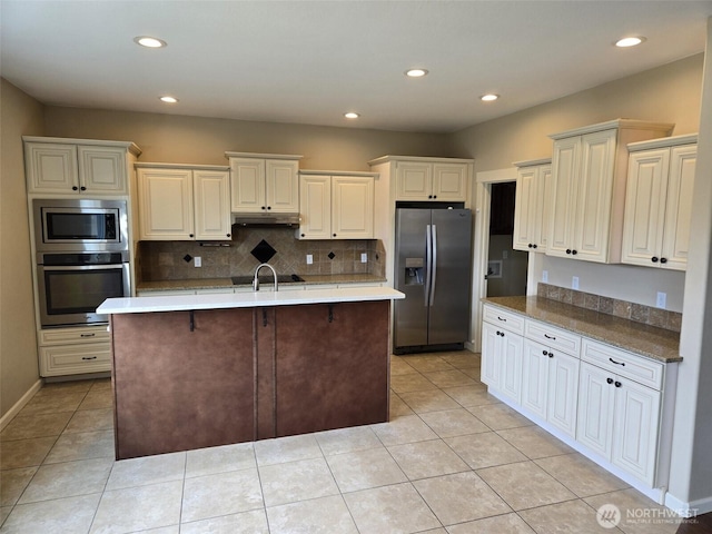 kitchen with recessed lighting, under cabinet range hood, a sink, stainless steel appliances, and backsplash