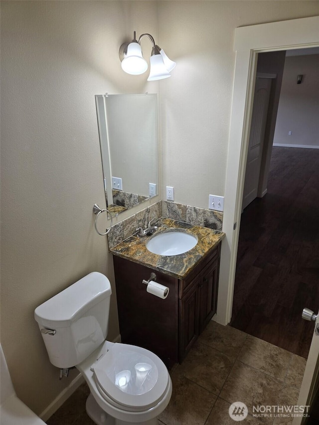 bathroom featuring baseboards, toilet, and vanity