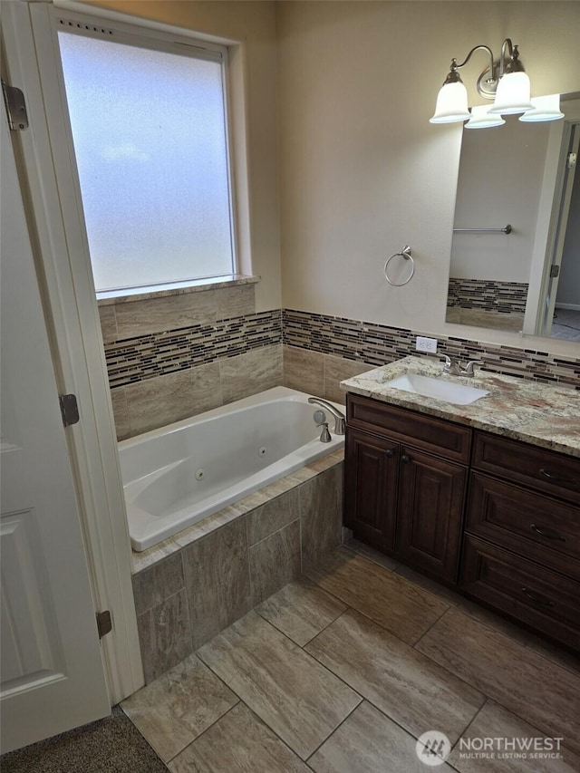 full bathroom featuring a jetted tub and vanity