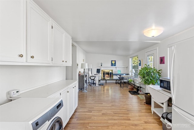 14043 Burke Ave N, Seattle, WA 98133 - washroom featuring washer / clothes dryer, light wood-type flooring, and a fireplace