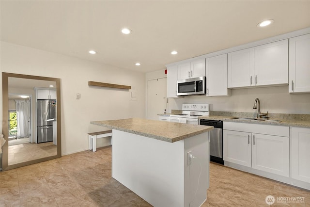 kitchen featuring a kitchen island, recessed lighting, white cabinetry, a sink, and appliances with stainless steel finishes