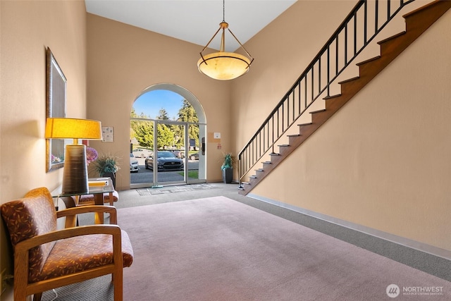 entrance foyer with carpet floors, baseboards, a high ceiling, and stairway