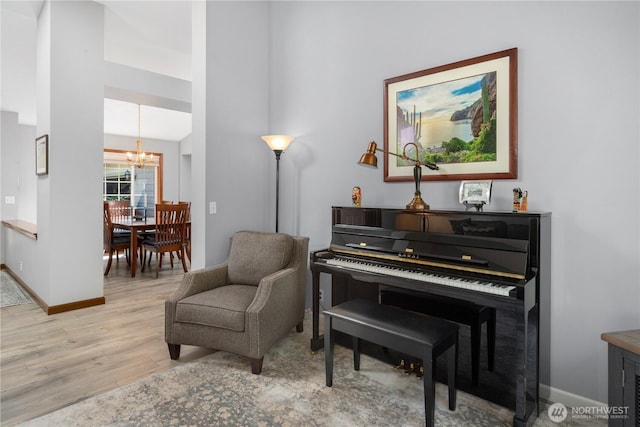 living area featuring a chandelier, light wood-type flooring, and baseboards