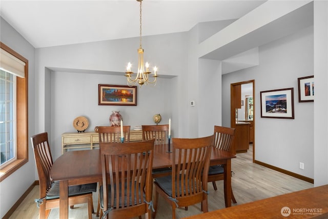 dining room featuring light wood-style flooring, a chandelier, baseboards, healthy amount of natural light, and lofted ceiling