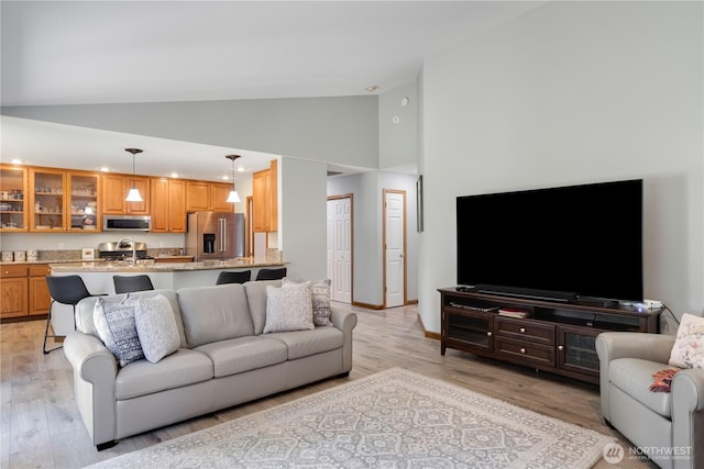 living room with light wood finished floors, high vaulted ceiling, and recessed lighting