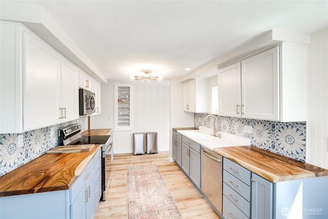1401 264th Pl, Ocean Park, WA 98640 - kitchen with decorative backsplash, butcher block countertops, light wood-type flooring, a sink, and appliances with stainless steel finishes