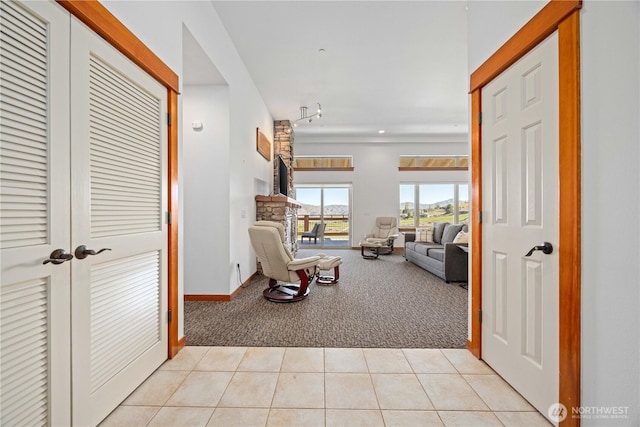 living area featuring track lighting, light carpet, light tile patterned flooring, and baseboards