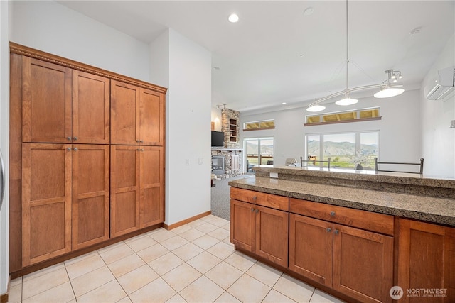 kitchen with an AC wall unit, dark countertops, brown cabinetry, decorative light fixtures, and light tile patterned floors