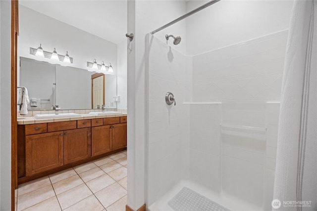 bathroom with tile patterned flooring, a sink, double vanity, and tiled shower