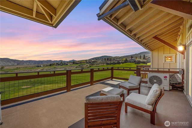 patio terrace at dusk with a lawn, a mountain view, ac unit, and outdoor lounge area