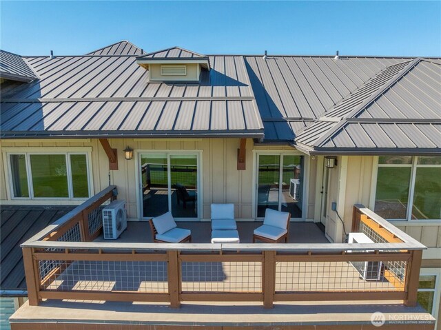 back of property with board and batten siding, ac unit, a standing seam roof, and metal roof
