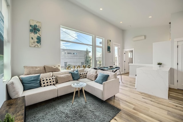 living room featuring light wood-style flooring, a wall unit AC, and recessed lighting