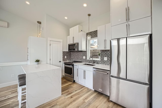 kitchen with white cabinetry, a center island, appliances with stainless steel finishes, a sink, and backsplash