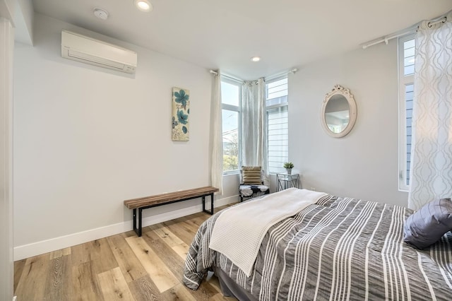 bedroom with light wood-type flooring, recessed lighting, baseboards, and a wall unit AC