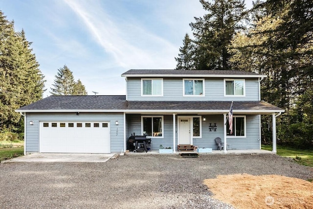traditional-style house with roof with shingles, a porch, an attached garage, and driveway