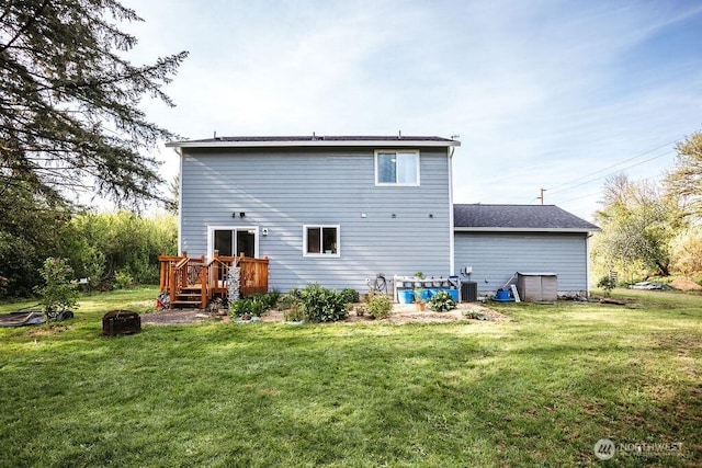 rear view of property with a lawn, a deck, central AC unit, and an outdoor fire pit