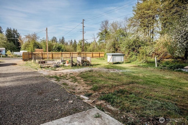 view of yard with a storage shed, fence, and an outbuilding