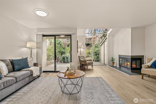 13730 15th Ave NE Unit F-103, Seattle, WA 98125 - living area featuring a multi sided fireplace and wood finished floors