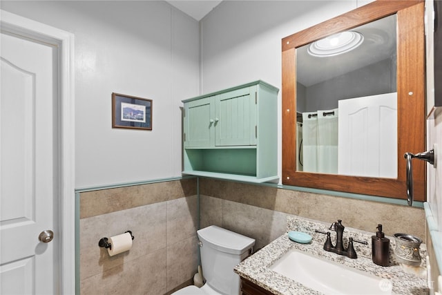 bathroom featuring vanity, tile walls, and toilet