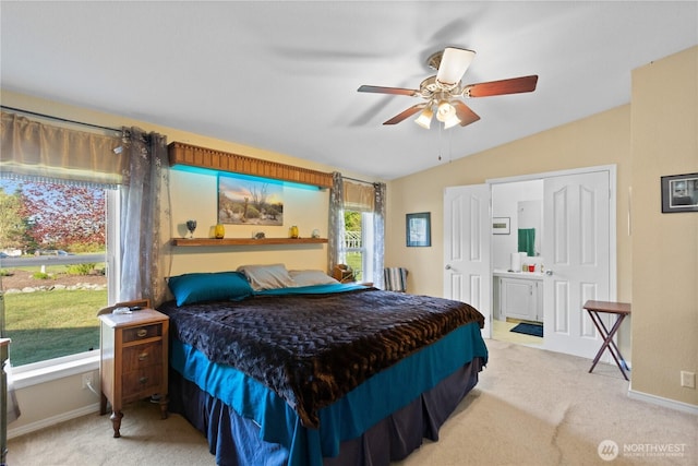 bedroom with ensuite bathroom, baseboards, light carpet, and lofted ceiling