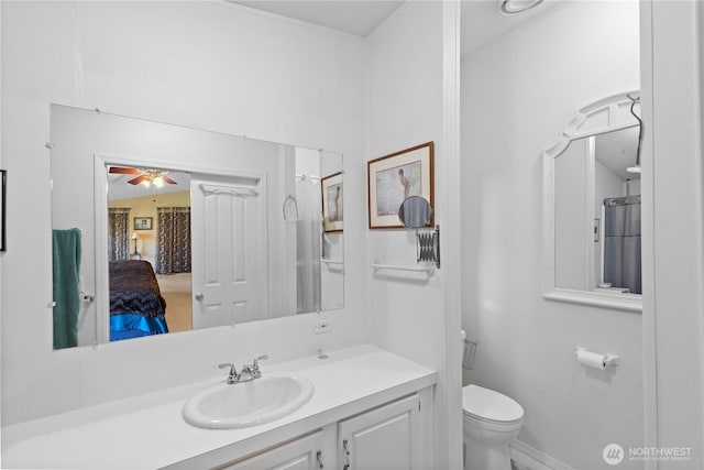 bathroom with toilet, vanity, ceiling fan, and baseboards