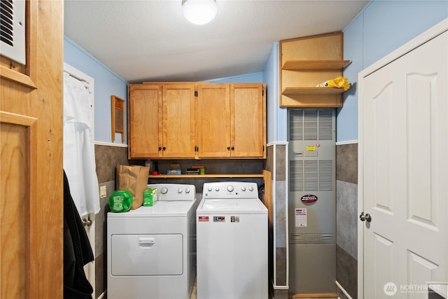 clothes washing area with independent washer and dryer, a textured ceiling, and cabinet space