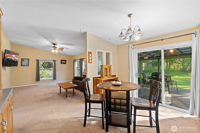 dining room with ceiling fan with notable chandelier, light colored carpet, baseboards, and lofted ceiling