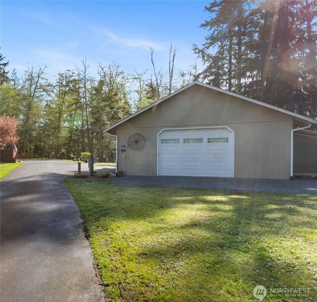 view of home's exterior with an outbuilding, stucco siding, a lawn, a garage, and driveway