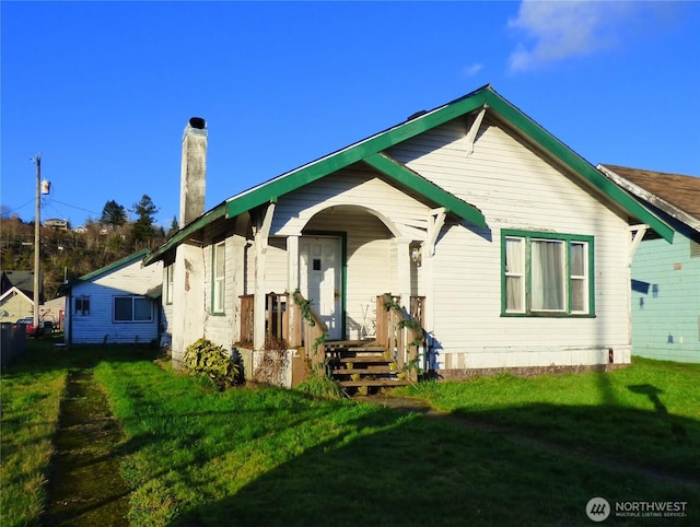 rear view of property featuring a yard and a chimney