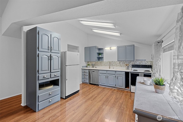 5675 Winona Ln, Langley, WA 98260 - kitchen with freestanding refrigerator, stainless steel dishwasher, electric range, vaulted ceiling, and a sink