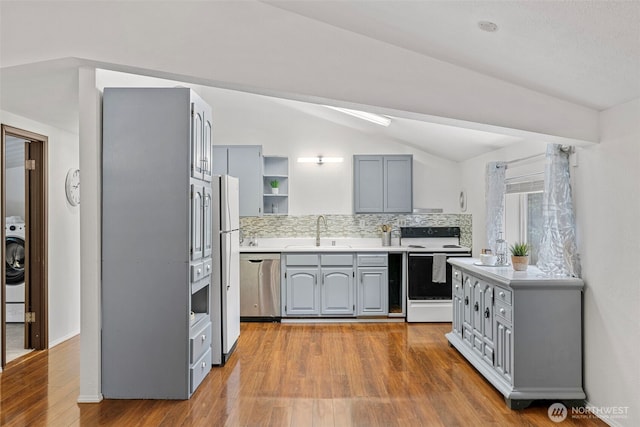 5675 Winona Ln, Langley, WA 98260 - kitchen featuring vaulted ceiling, white appliances, gray cabinetry, decorative backsplash, and a sink