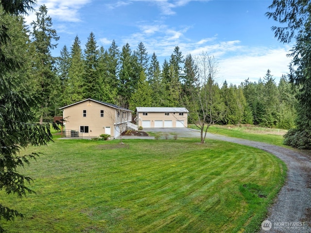 5675 Winona Ln, Langley, WA 98260 - view of front facade with an outbuilding, driveway, a garage, a forest view, and a front yard