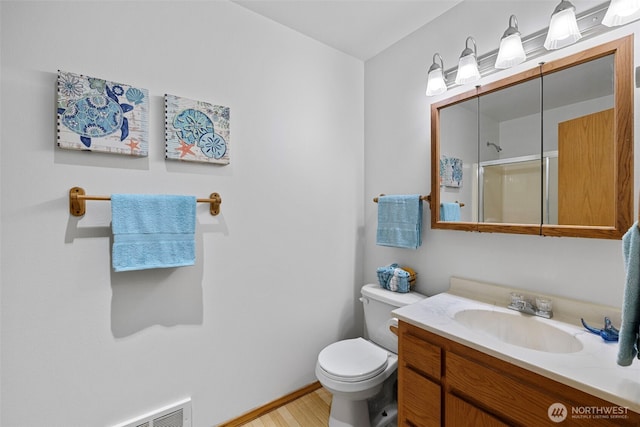 5675 Winona Ln, Langley, WA 98260 - full bathroom with a shower with shower door, toilet, baseboards, wood finished floors, and vanity