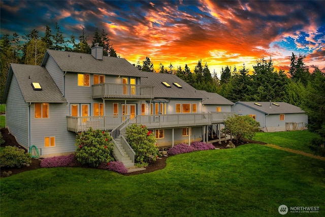 rear view of house featuring a shingled roof, a lawn, a chimney, stairs, and a balcony