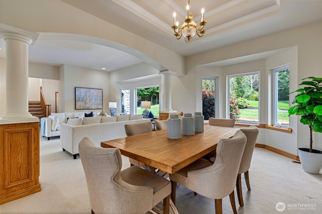 dining room featuring decorative columns, a tray ceiling, arched walkways, light colored carpet, and ornamental molding