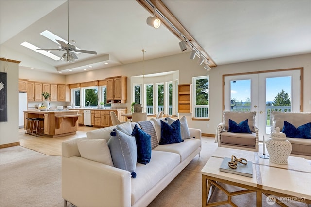 living room with ceiling fan, track lighting, a skylight, french doors, and baseboards