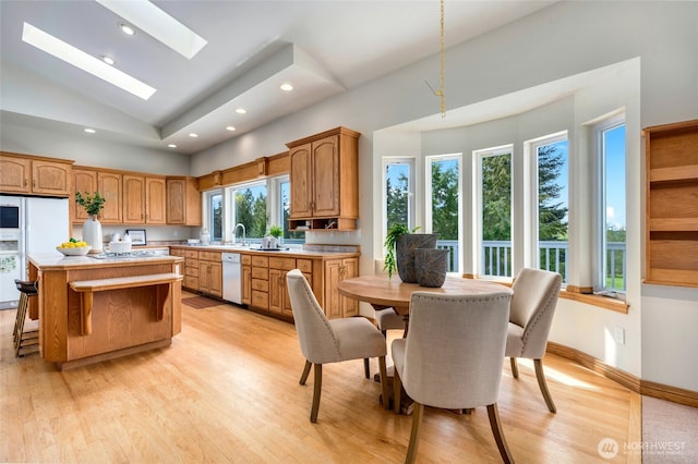 kitchen with recessed lighting, white appliances, light countertops, a kitchen island, and light wood-style floors