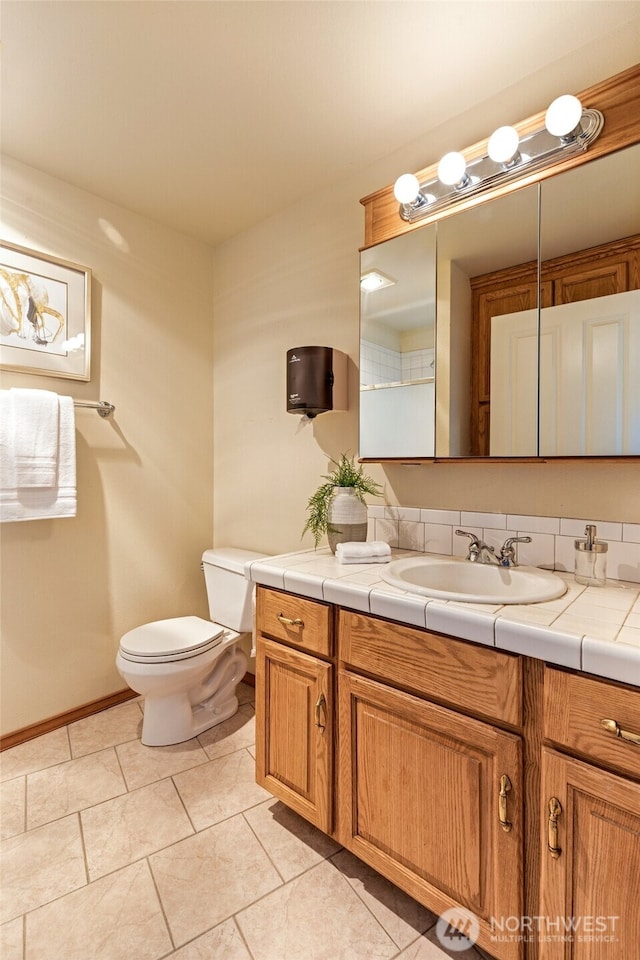 bathroom featuring tile patterned floors, toilet, vanity, and baseboards