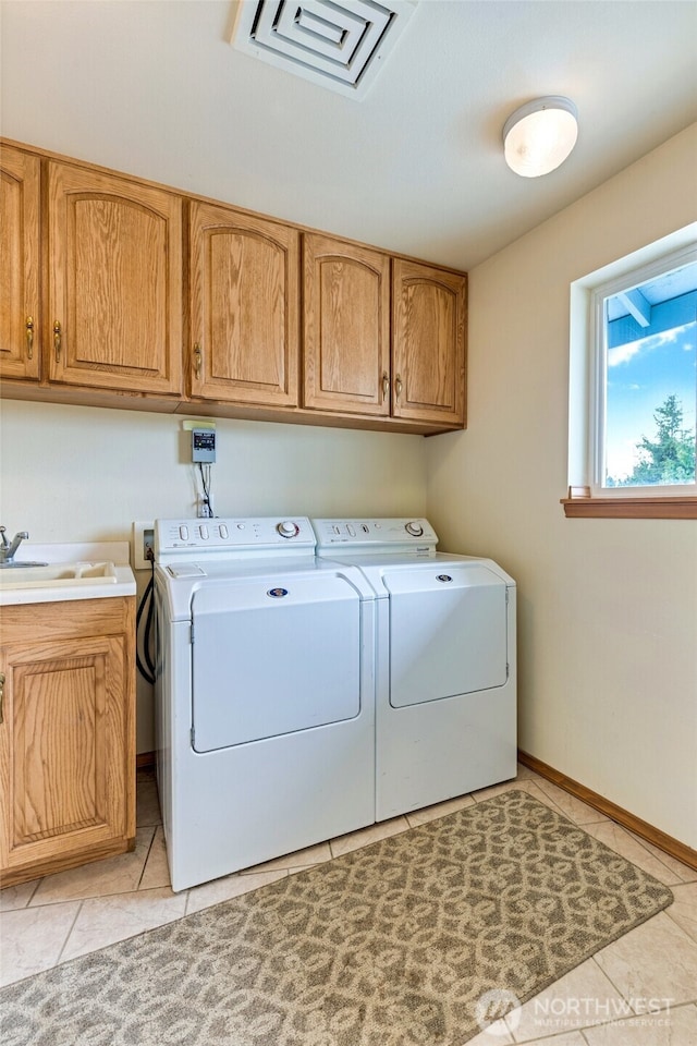 washroom with light tile patterned floors, visible vents, a sink, washer and dryer, and cabinet space