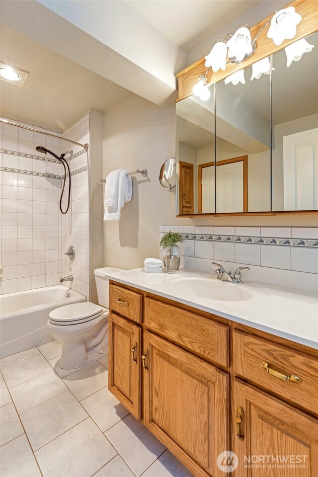 bathroom featuring toilet, vanity, shower / tub combination, tile patterned flooring, and decorative backsplash