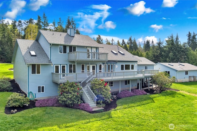 rear view of house with a yard, a wooden deck, a chimney, and stairs
