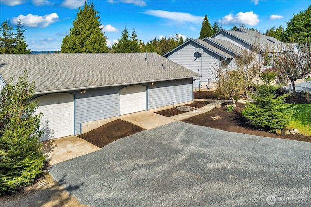 exterior space with a shingled roof and a garage