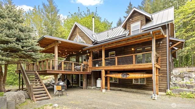 rear view of property featuring a standing seam roof, a wooden deck, stairs, and metal roof