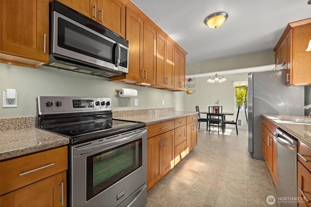 19529 Locust Way, Lynnwood, WA 98036 - kitchen with appliances with stainless steel finishes, brown cabinets, a chandelier, and light stone countertops