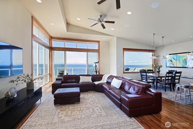 living area featuring a ceiling fan, wood finished floors, a water view, and a healthy amount of sunlight