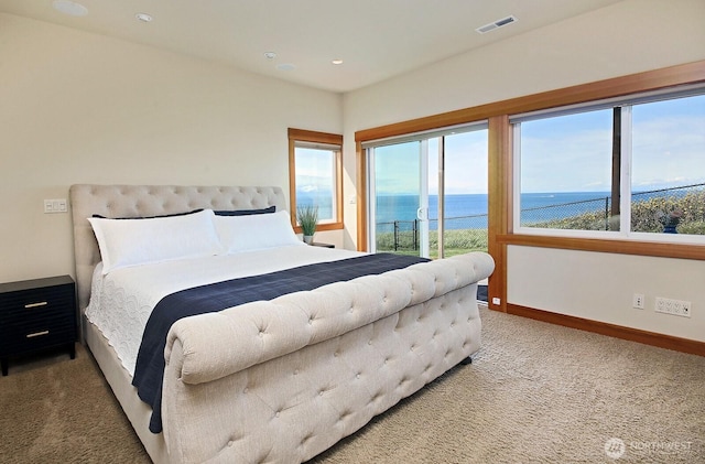 bedroom with carpet, visible vents, access to exterior, a water view, and baseboards