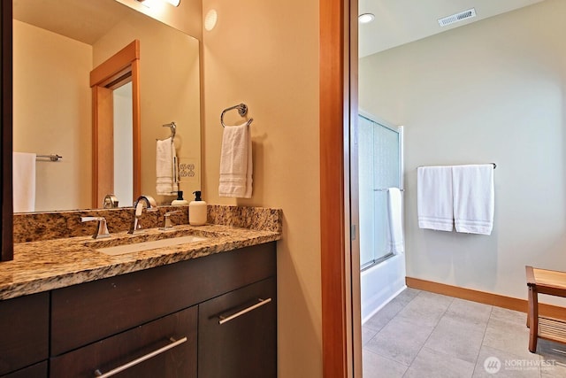 bathroom featuring tile patterned flooring, visible vents, vanity, baseboards, and bath / shower combo with glass door