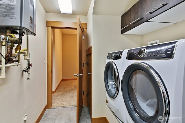 clothes washing area with washer and dryer, baseboards, cabinet space, and light tile patterned flooring