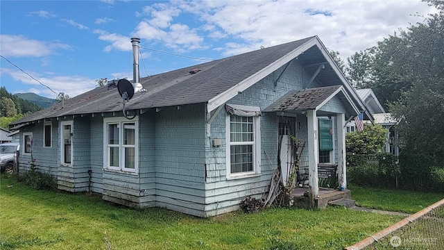 view of side of property featuring a lawn and roof with shingles
