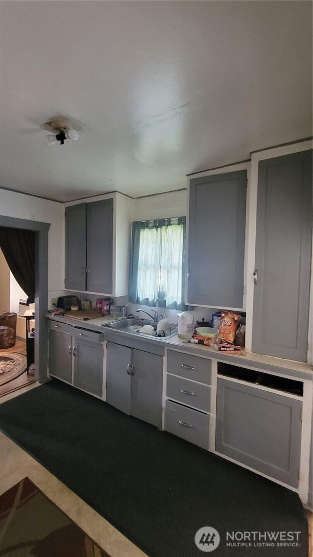 kitchen with gray cabinets, a sink, and light countertops